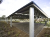 Steel building roof over school sports court with gable infill roof and round safety posts - Melbourne, Victoria